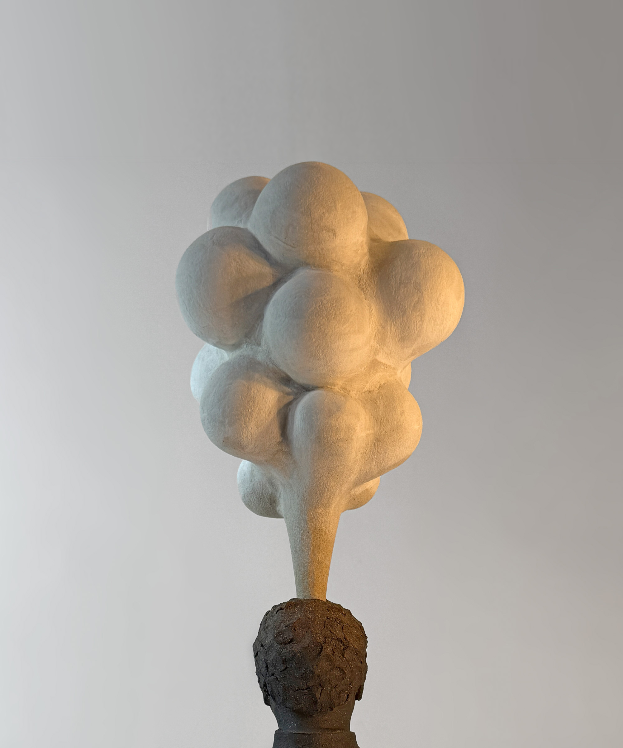 ceramic sculpture of a monk cliimbing a mountain and a sphere behind the mountain